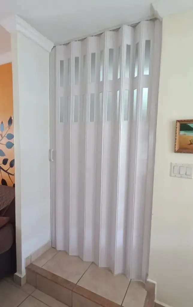 Puerta plegable corrediza - Plástica (PVC) - Con ventanillas de cristal acrílico - Fabricación a medida